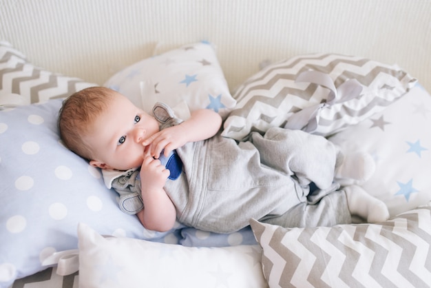 Hermoso bebé recién nacido acostado en almohadas en delicados tonos grises, azules y blancos