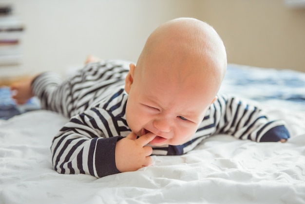 Hermoso bebé recién nacido acostado en su cama y llorando