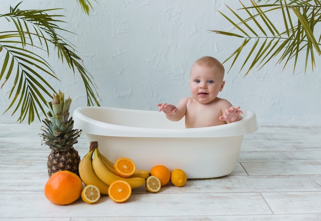 Hermoso bebé se sienta en una tina de frutas cítricas sobre una superficie de madera con un lugar para el texto