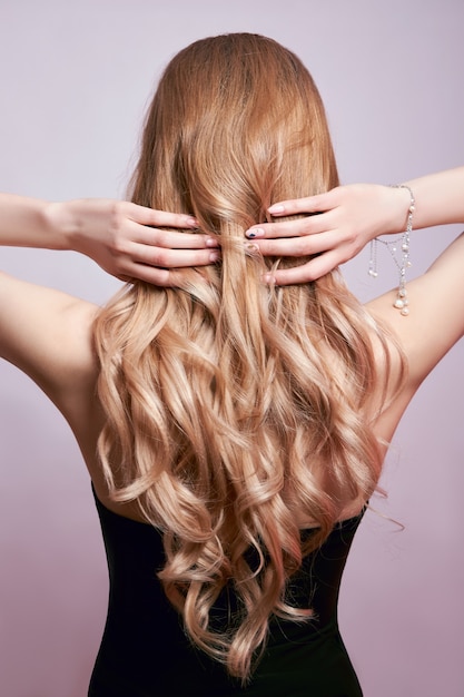 Hermoso cabello fuerte de mujer, fortaleciendo y restaurando las raíces del cabello. Hermosa manicura en manos de una niña.