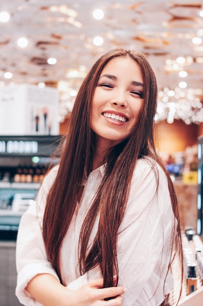 El hermoso cabello largo asiático sonriente joven mujer en tienda supermercado de cosméticos, perfumes, duty free