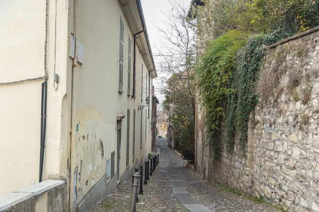 Hermoso callejón estrecho con muchas ventanas y hiedra verde en el muro de piedra en la ciudad de Brescia. Arquitectura histórica de la región de Lombardia en Italia. Viaje de invierno en el norte de Italia. Viajando por Europa.