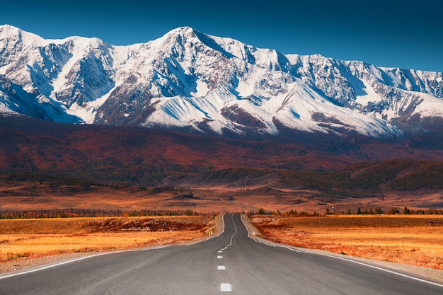 Hermoso camino en las montañas de otoño. Tracto Chuysky y vista de la cordillera North-Chuya en Altai, Siberia, Rusia. Picos nevados y bosque otoñal amarillo