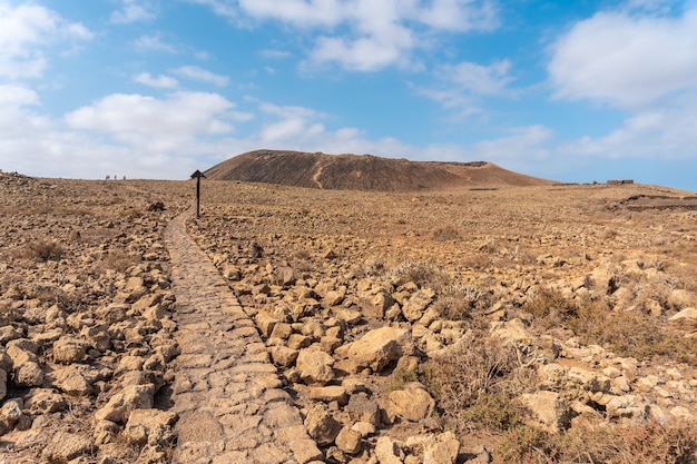 Hermoso camino de piedra hacia el cráter del volcán Calderón Hondo cerca de Corralejo, costa norte de la isla de Fuerteventura, Islas Canarias. España