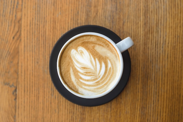 Hermoso capuchino con arte en una taza blanca. Vista superior, de cerca.