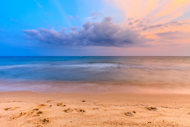 Hermoso cielo al atardecer y playa tropical y olas del mar