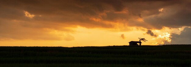 Hermoso cielo al atardecer con silueta de cabaña