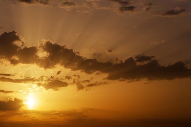 Hermoso cielo anaranjado al atardecer con rayos de sol.