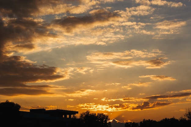 Hermoso cielo anaranjado al atardecer sobre la pequeña ciudad. Siluetas oscuras de edificios en el crepúsculo.