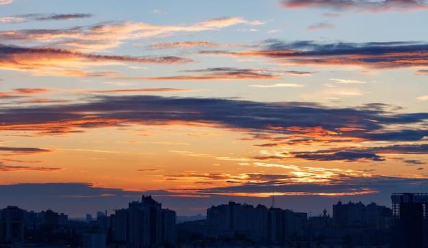 Hermoso cielo ardiente sobre la silueta de la ciudad a la hora azul.