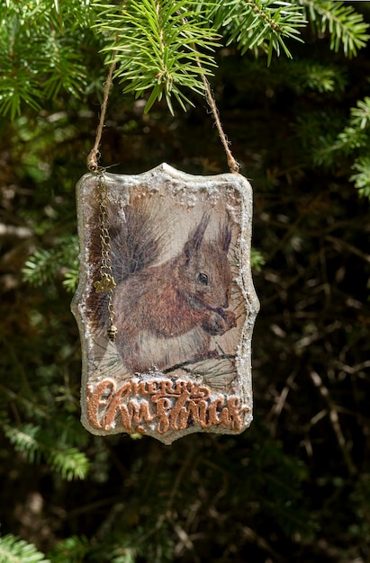 Foto hermoso colgante de navidad o año nuevo con ardilla colgando de una rama de abeto en el bosque