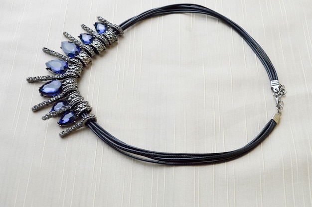 Un hermoso collar de moda femenino en una banda de goma negra con diamantes de gemas brillantes azules