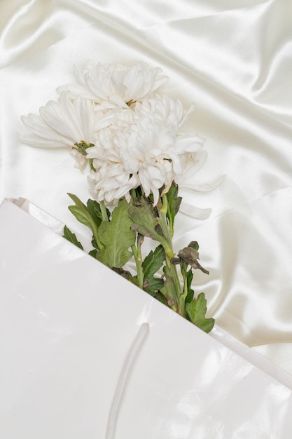 Hermoso concepto de flor Ramo de crisantemo blanco en bolsa sobre fondo de tela blanca