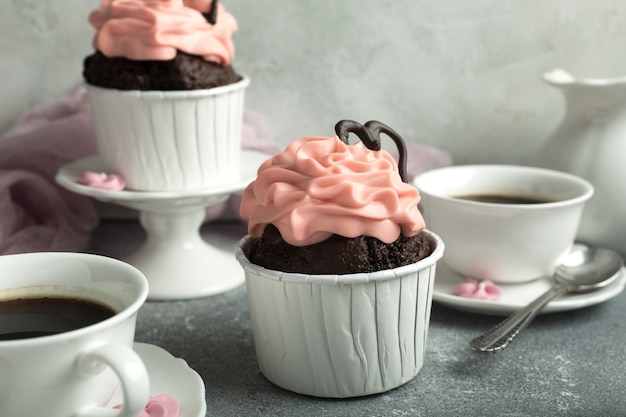 Hermoso cupcake de chocolate, crema rosa y corazón sobre la superficie de piedra gris. San Valentín, día de la madre, concepto de boda con espacio de copia. Estilo retro entonado