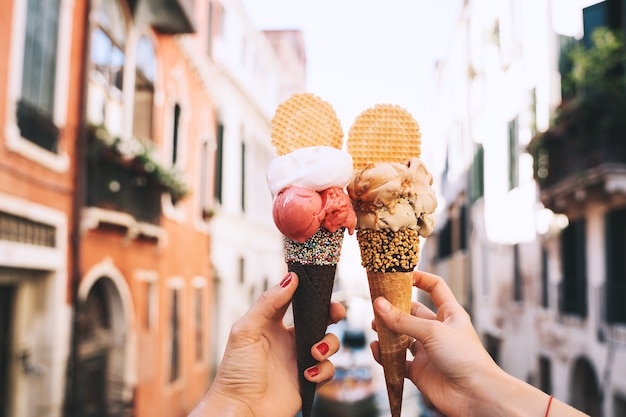 Hermoso y delicioso helado italiano en cono de galleta frente a las calles y puentes de Venecia