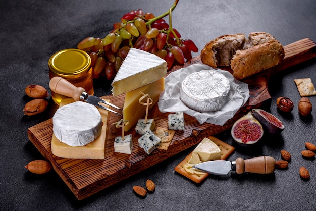 Hermoso delicioso queso camembert, parmesano, brie con uvas e higos sobre una tabla de madera. Aperitivos para vino en vacaciones