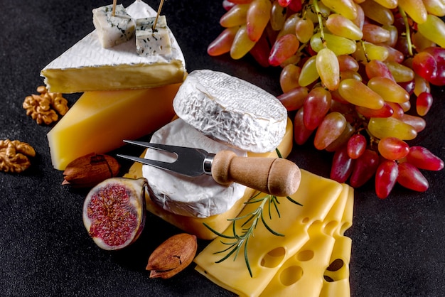 Hermoso delicioso queso camembert, parmesano, brie con uvas e higos sobre una tabla de madera. Snacks para vino