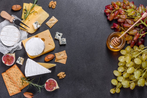 Hermoso delicioso queso camembert, parmesano, brie con uvas e higos sobre una tabla de madera.