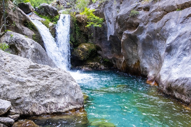 Un hermoso desfiladero de montaña con un río y una cascada.