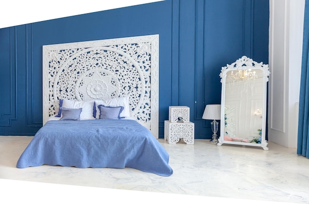 Hermoso dormitorio interior limpio clásico de lujo en color blanco y azul profundo con cama kingsize y c