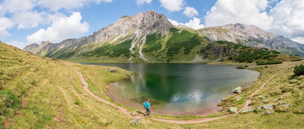 Hermoso e idílico paisaje montañoso lago cordillerano con agua clara y cielo azul nublado Panorama