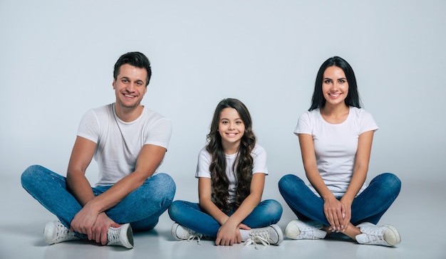 Hermoso emocionado y el divertido equipo de la familia está posando con una camiseta blanca mientras aislados sobre fondo blanco en el estudio.