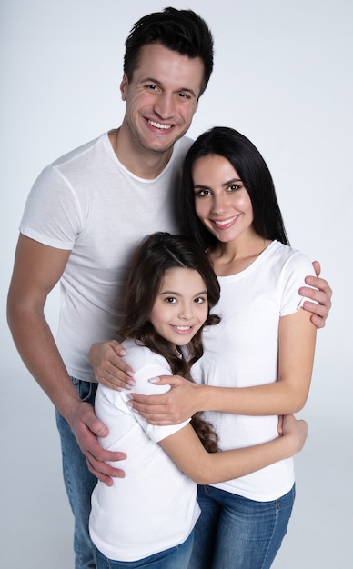 Hermoso emocionado y el divertido equipo de la familia está posando con una camiseta blanca mientras aislados sobre fondo blanco en el estudio.