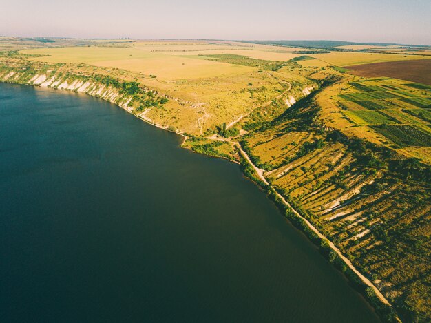 Hermoso espacio terrestre de drones aéreos de río o lago con increíbles colinas verdes durante el verano.