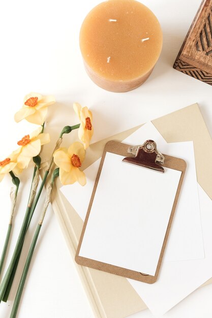 Hermoso espacio de trabajo de escritorio de mesa de oficina en casa con flores frescas de narciso, ataúd de madera, velas, álbumes