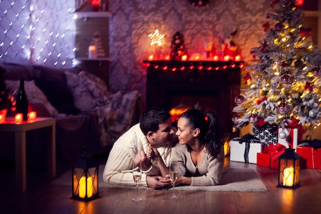 Hermoso esposo y esposa en luz tenue celebrando la Navidad. Árbol de Navidad.