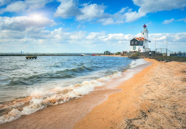 Hermoso faro en la costa del mar y cielo azul con nubes al atardecer en primavera en Holanda. Paisaje con arena amarilla, mar y baliza. Paisaje marino. Paisaje marino por la noche en Europa