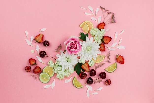 Hermoso flatlay de varias frutas, bayas y flores en rosa