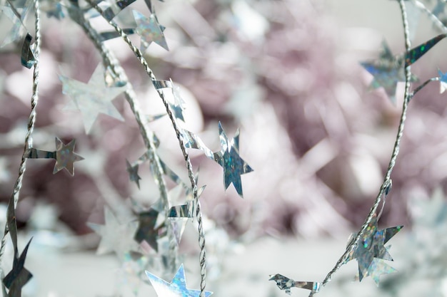 Hermoso fondo de año nuevo de alambre trenzado plateado con estrellas en un rosa pálido borroso