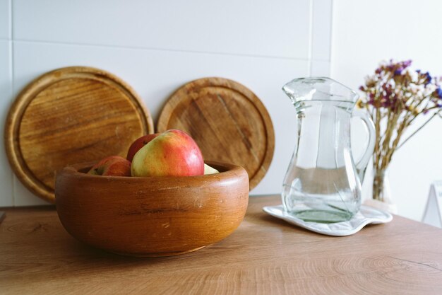 hermoso fondo de la cocina colores claros plato de madera con ramo de frutas flores jarro de vidrio agua