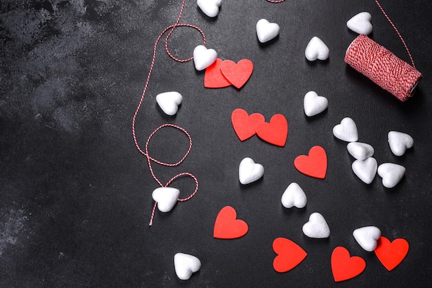 Hermoso fondo con corazones blancos y rojos sobre una mesa oscura. Preparándonos para el día de los enamorados