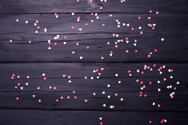 Hermoso fondo del día de San Valentín con corazones rojos sobre fondo negro de madera.