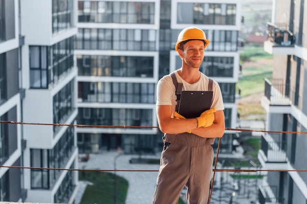 Hermoso fondo Joven trabajando en uniforme en la construcción durante el día