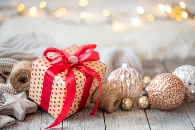 Hermoso fondo de Navidad con juguetes de Navidad y una caja de regalo con un lazo rojo. El concepto de saludos y celebraciones de año nuevo.