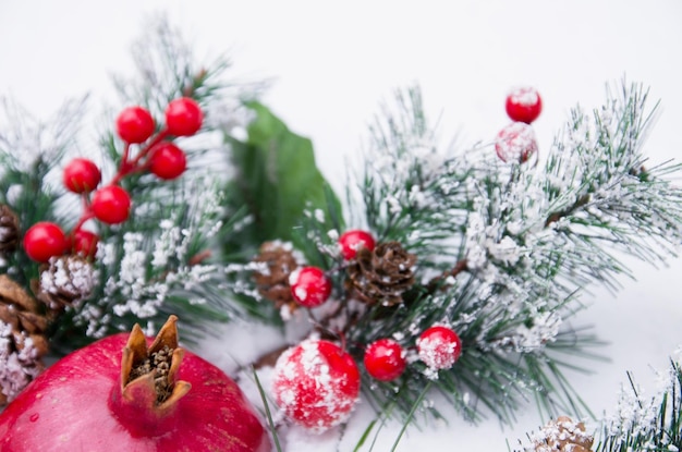 Hermoso fondo navideño con frutas de granada y ramas de abeto en la temporada de invierno con nieve