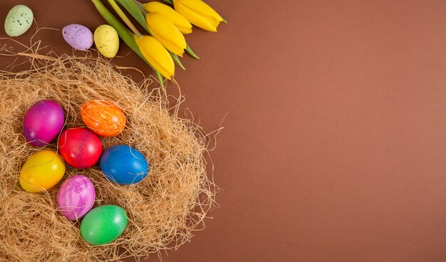 Hermoso grupo de huevos de Pascua en la primavera del día de Pascua, huevos rojos, azules, morados y amarillos en canasta de madera sobre el fondo marrón