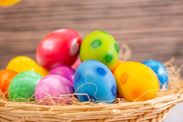 Hermoso grupo de huevos de Pascua en la primavera del día de Pascua, huevos rojos, azules, morados y amarillos en la cesta de madera en el fondo de la mesa de madera