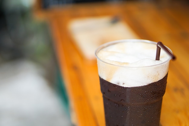 Hermoso helado Americano o café negro con espuma de granos de café recién hechos