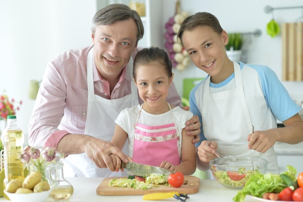 Hermoso hermano y hermana y padre cocinando juntos en la cocina