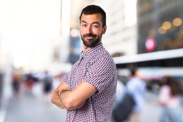 Hermoso hombre con los brazos cruzados sobre fondo desenfocado