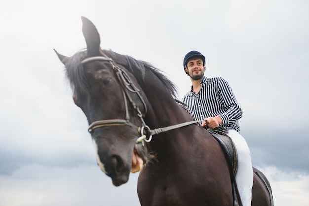 Hermoso hombre a caballo en el campo en verano