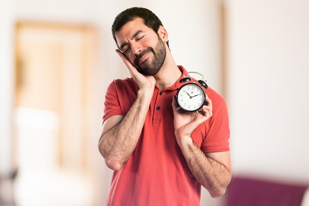 Hermoso hombre celebración vintage reloj en el fondo desenfocado