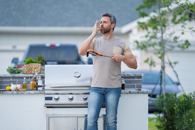 Hermoso hombre hispano sonriente haciendo barbacoa en el patio trasero picnic barbacoa fiesta jefe de cocina con