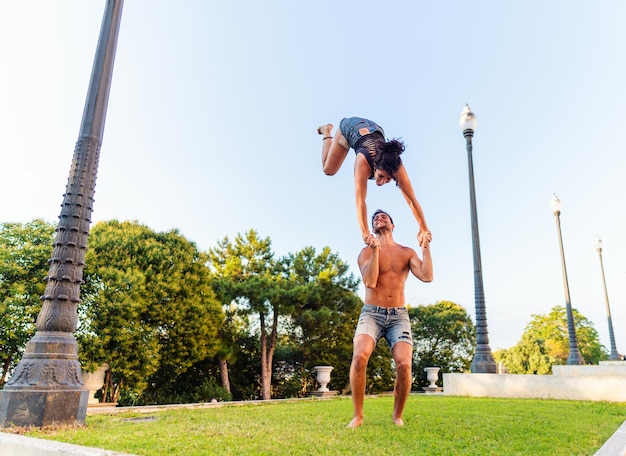 Hermoso hombre y mujer haciendo acroyoga en el césped del parque de la ciudad Armonía y relajación