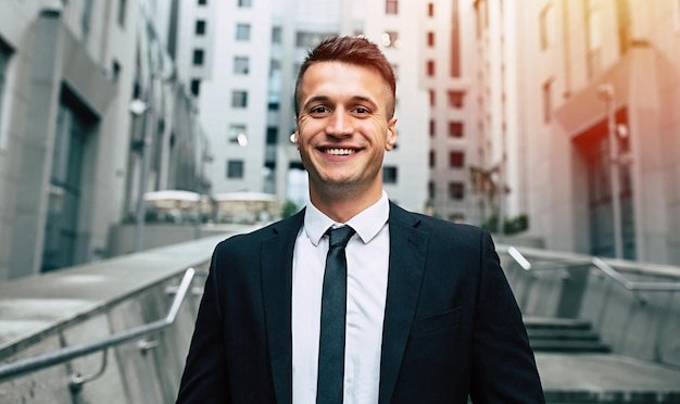 Hermoso hombre de negocios sonriente y exitoso en un traje negro de moda mira a la cámara