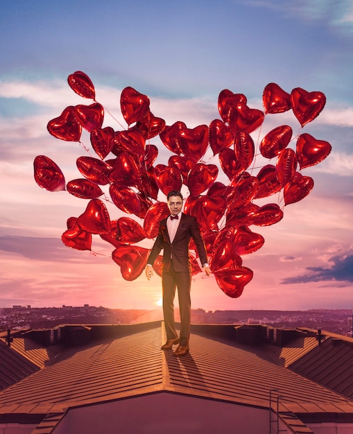 Hermoso hombre en el techo con globos de corazón